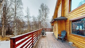 A wooden deck with a red railing, a table, and two chairs. - Remote 2BR Log Cabin Tucked Outside Anchorage (Eagle River)