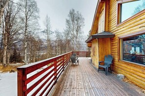 A wooden deck with a red railing, a table, and two chairs. - Remote 2BR Log Cabin Tucked Outside Anchorage (Eagle River)