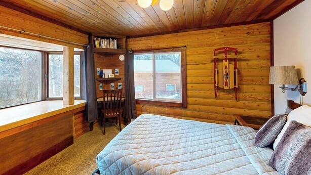 A wooden cabin room with a bed, a desk, and a window. - Remote 2BR Log Cabin Tucked Outside Anchorage (Eagle River)