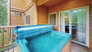Eine Holzterrasse mit Whirlpool und einer überdachten Fläche.