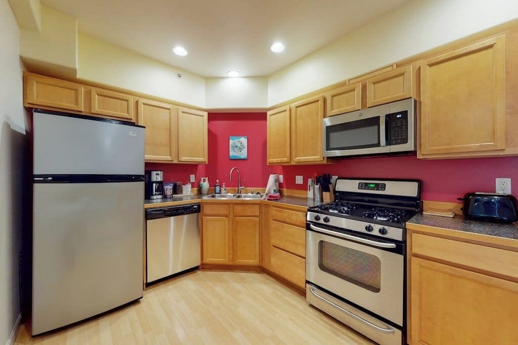 Una cocina con armarios de madera, un refrigerador de acero inoxidable, un microondas, una estufa y un lavavajillas.