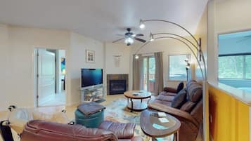 A living room with a sofa, a coffee table, a television, and a fireplace.