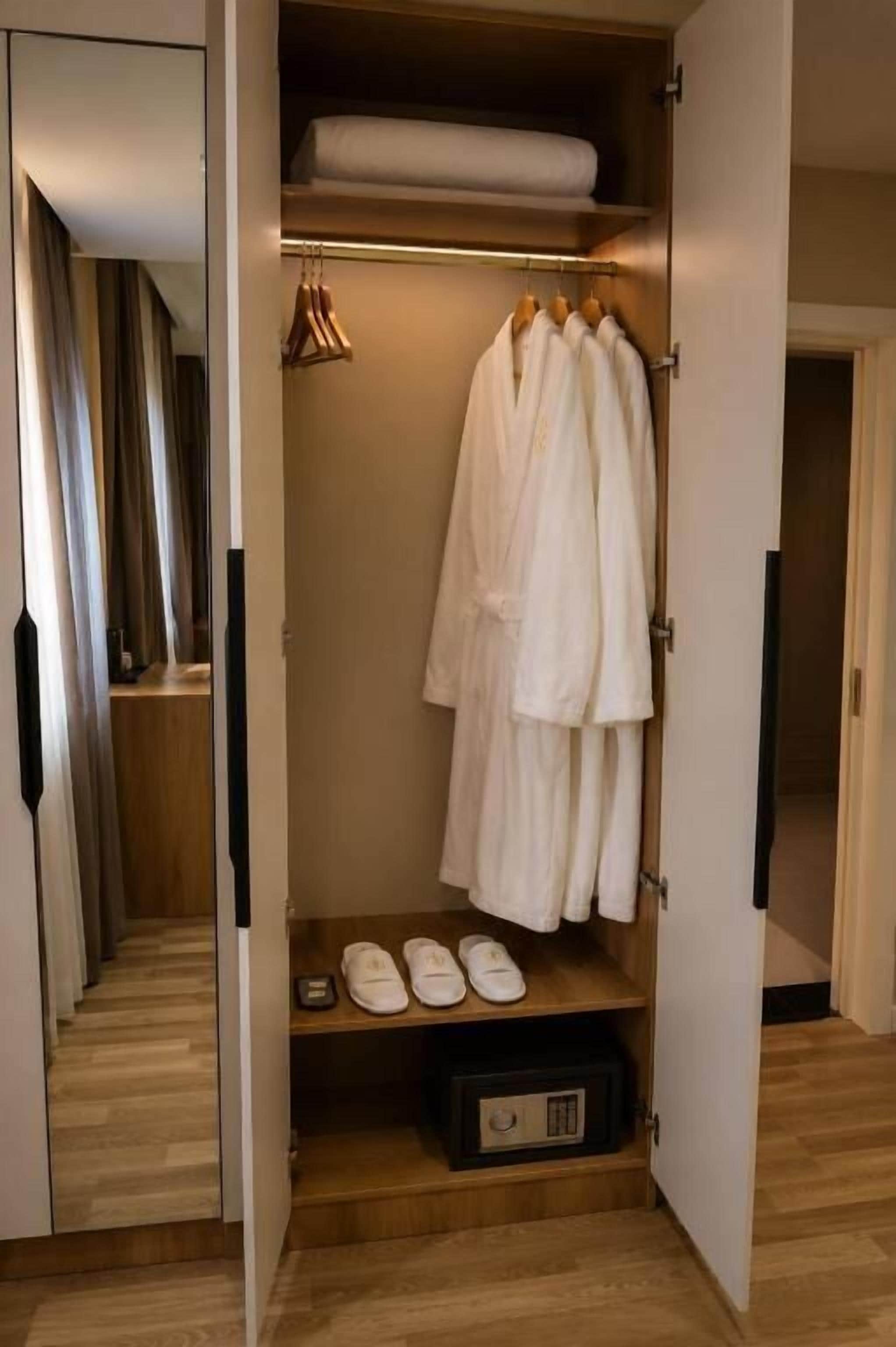 A walk-in closet with hanging robes, a shelf with shoes, and a storage box.