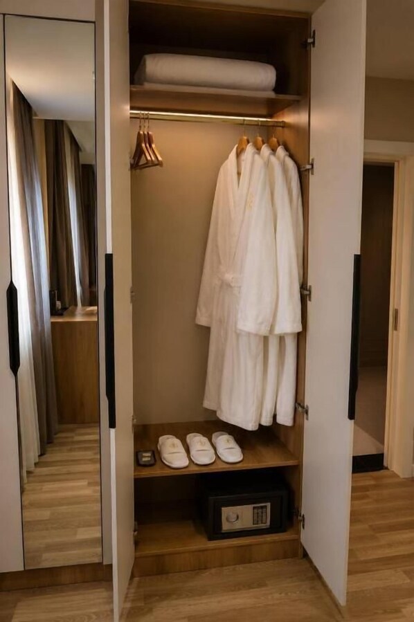 A walk-in closet with hanging robes, a shelf with shoes, and a storage box.