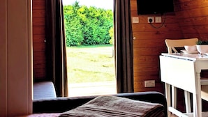 Une pièce confortable avec un plafond en bois, un lit, un bureau avec une chaise et un téléviseur fixé au mur.