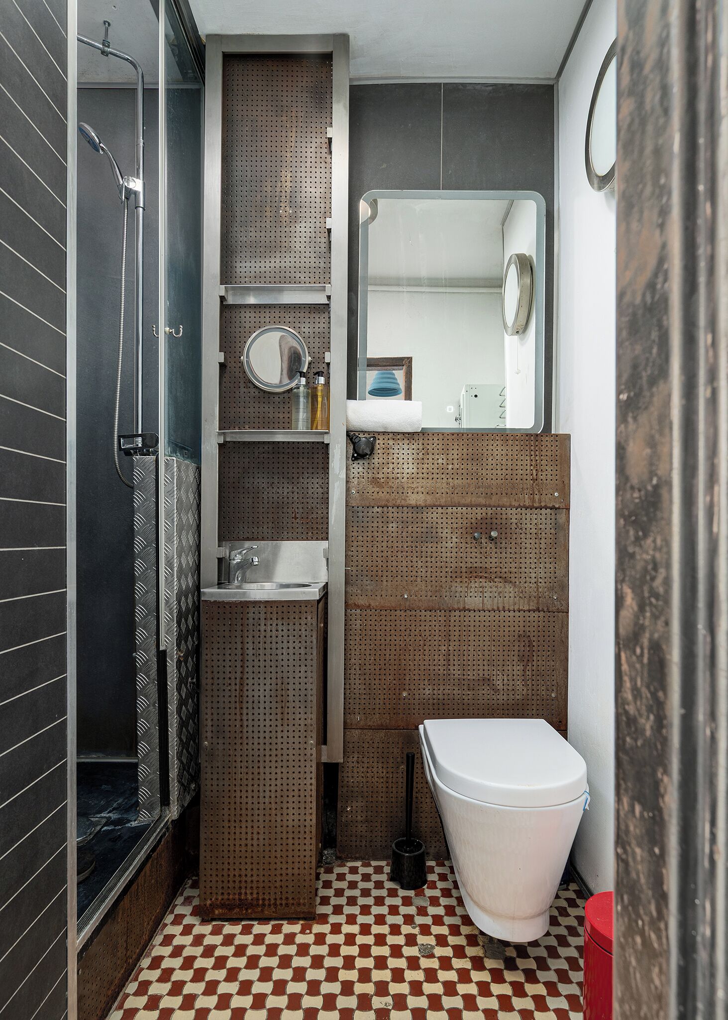 Un baño pequeño con ducha, lavamanos, inodoro y espejo.