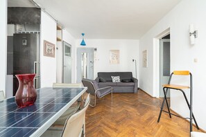 A modern living space with a dining area, a sofa, and a chair. - RentPlanet - Apartament Żelazna (Warszawa)