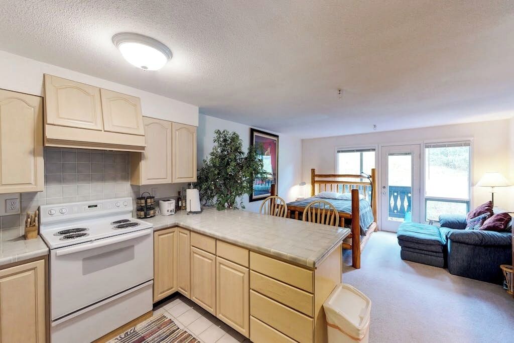 A compact kitchen with a stove, cabinets, and a dining area with a table and chairs.