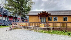 A building with a wooden facade and a covered porch, surrounded by a wooden fence with bike parking signs. - Slopeside Studio at Alyeska w/ Full Kitchen (Girdwood)