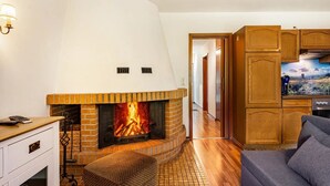 Una sala de estar con chimenea, armarios de madera y un televisor.
