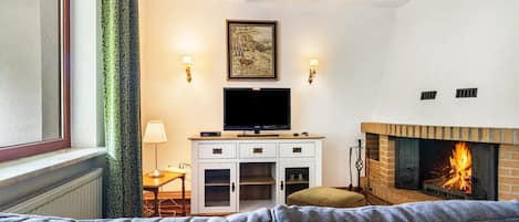 Un salon avec une cheminée, un téléviseur et un canapé.