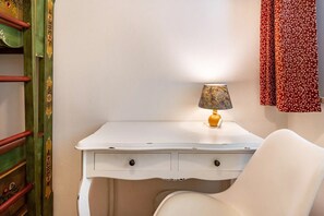 Ein weißer Schreibtisch mit Lampe, einem Stuhl und einer Holzleiter.