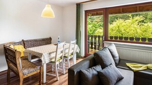Una habitación acogedora con una mesa de comedor, sillas, un sofá y un ventanal con vistas a zonas verdes.