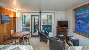 A room with a dining table, chairs, a fireplace, a television, and a painting.