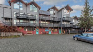 A multi-story building with balconies, a bakery shop, and a parking area.