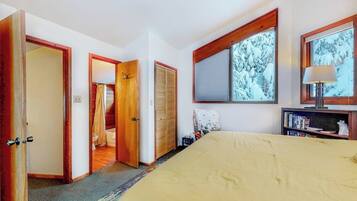 A bedroom with a bed, a wardrobe, a mirror, and a window with a view of trees.