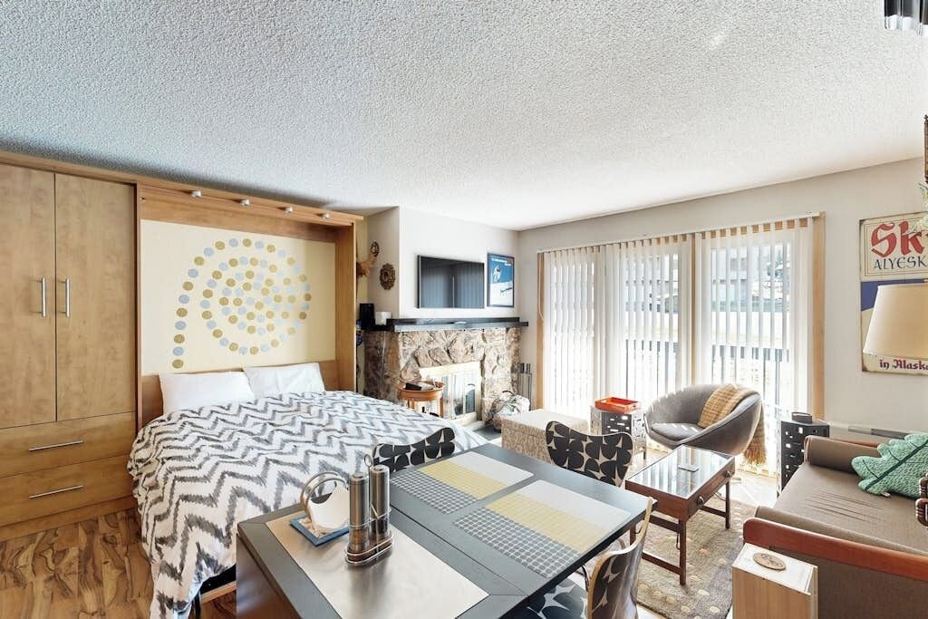 A hotel room with a bed, a desk, a chair, a sofa, and a fireplace.