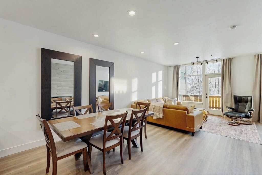A modern living room with a dining area, a sofa, and a chair.