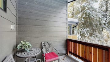 A balcony with a wooden railing, a small round table, and two chairs.