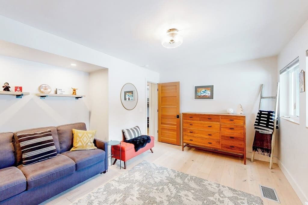 A living room with a sofa, a coffee table, a wooden dresser, and a door leading to another room.