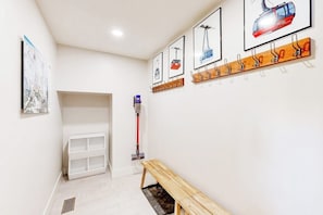 A hallway with a bench, a coat rack, and framed pictures on the wall.