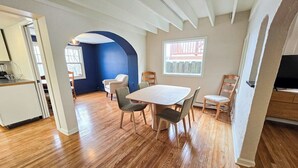 Un comedor con una mesa y sillas de madera, una zona de cocina con refrigerador y una pared azul decorativa.