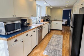 Eine moderne Küche mit weißen Schränken, einer Edelstahl-Mikrowelle, einer Kaffeemaschine und einem Kühlschrank.