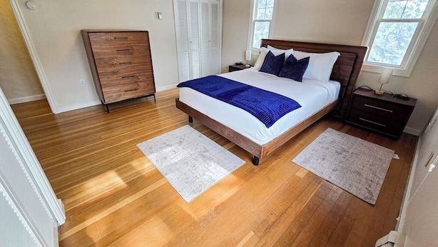 Un dormitorio con una cama de madera, dos mesitas de noche, un tocador y una ventana.