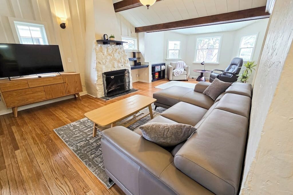 Ein Wohnzimmer mit einer Couch, einem Couchtisch, einem Flachbildfernseher, einem Kamin und einer Wand aus Stein.