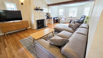 A living room with a sofa, a coffee table, a flat-screen TV, a fireplace, and a stone accent wall.
