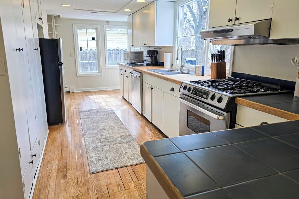A modern kitchen with a stove, sink, and cabinets.