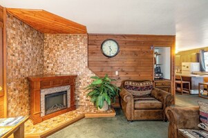 Una sala de estar con chimenea, un reloj en la pared y un sofá.