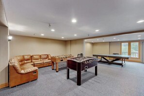 A room with a foosball table, a sofa, and a ping pong table. - Quiet Girdwood Studio w/ Easy Access to the Village (Girdwood)