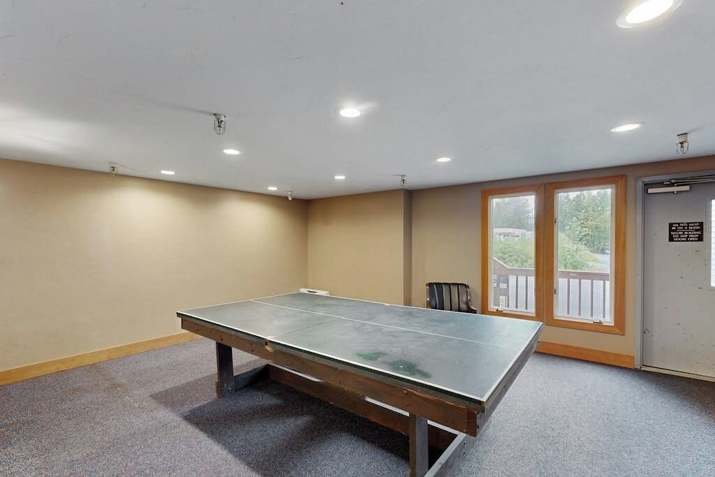 A room with a ping pong table, a chair, and a door with a sign.