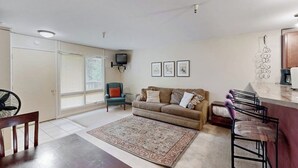 Ein Wohnzimmer mit einer Couch, einem Couchtisch, einem Fernseher und einem Essbereich mit Stühlen.