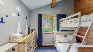 Habitación con literas, un aparador y una pared decorada con calcomanías de pájaros.