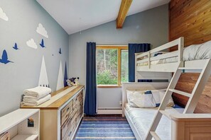 Habitación con literas, un aparador y una pared decorada con calcomanías de pájaros.