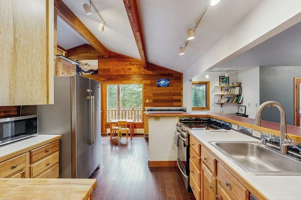 Una cocina con vigas de madera, un comedor con vistas y una isla grande con un lavabo.