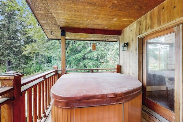 A hot tub on a wooden deck with a view of trees.