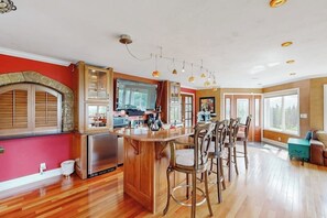 A kitchen with a central island, bar stools, and a stone archway. - South Anchorage Apartment w/ Shared Deck & Wildlife (Anchorage)