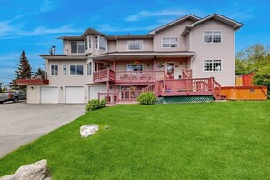 A two-story house with a front porch, a garage, and a well-maintained lawn. - South Anchorage Apartment w/ Shared Deck & Wildlife (Anchorage)