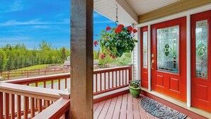 Eine Holzterrasse mit einer roten Tür und einem hängenden Blumentopf.