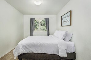 Un dormitorio con cama, cortinas, una ventana y un cartel en la pared.