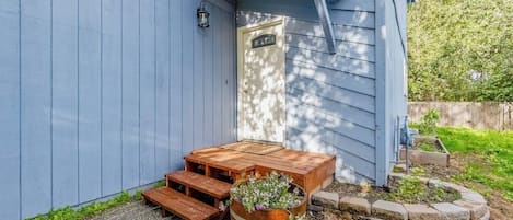 Un patio in legno con una panchina e un fioriere con fiori.