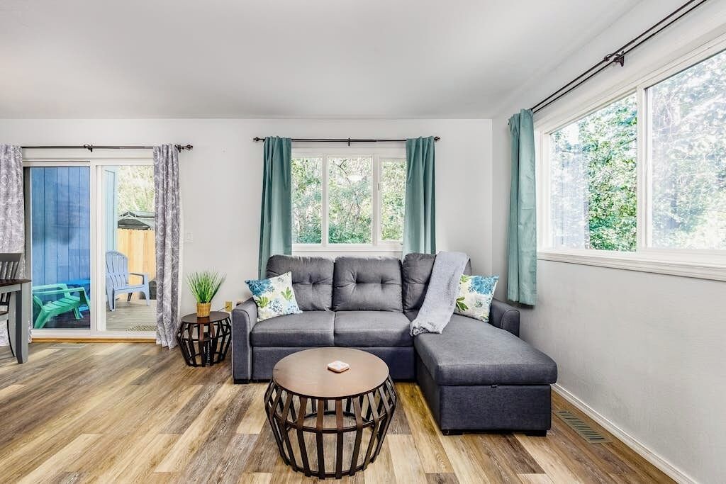 A modern living room with a sectional sofa, a round coffee table, and a sliding glass door leading to an outdoor area.