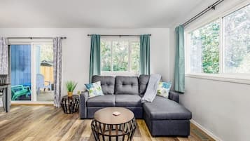 A modern living room with a sectional sofa, a round coffee table, and a sliding glass door leading to an outdoor area.