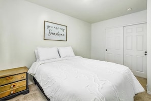A bedroom with a bed, a bedside table, a dresser, and a wall-mounted picture frame. - Quiet Anchorage Neighborhood Home w/ Walking Trail (Anchorage)