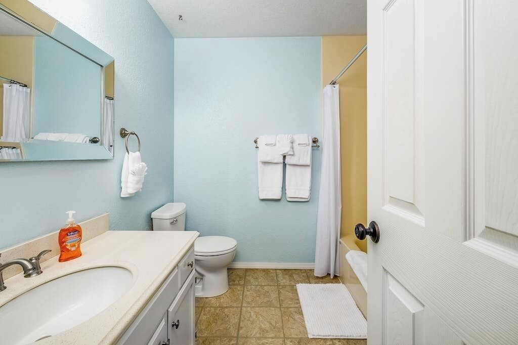 A bathroom with a sink, toilet, and a mirror.