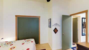 A bedroom with a bed, a door, a wall-mounted light fixture, and a door with a window.