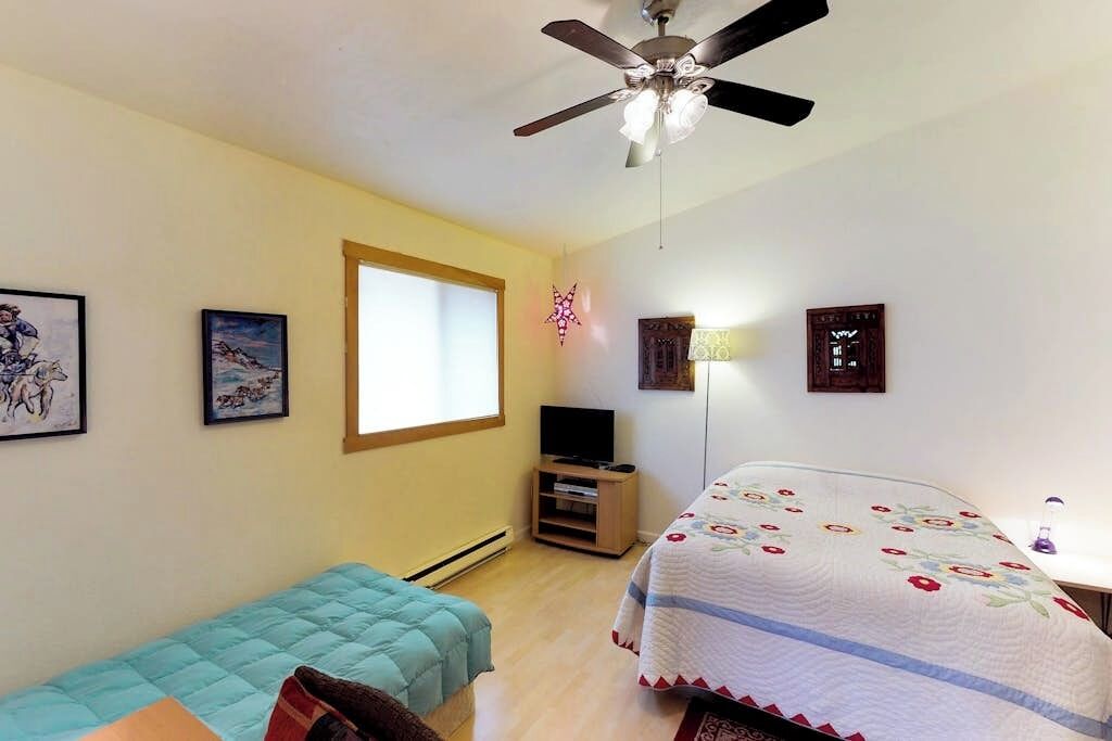 Une chambre à coucher avec un lit, un ventilateur de plafond, une fenêtre et des décorations murales.
